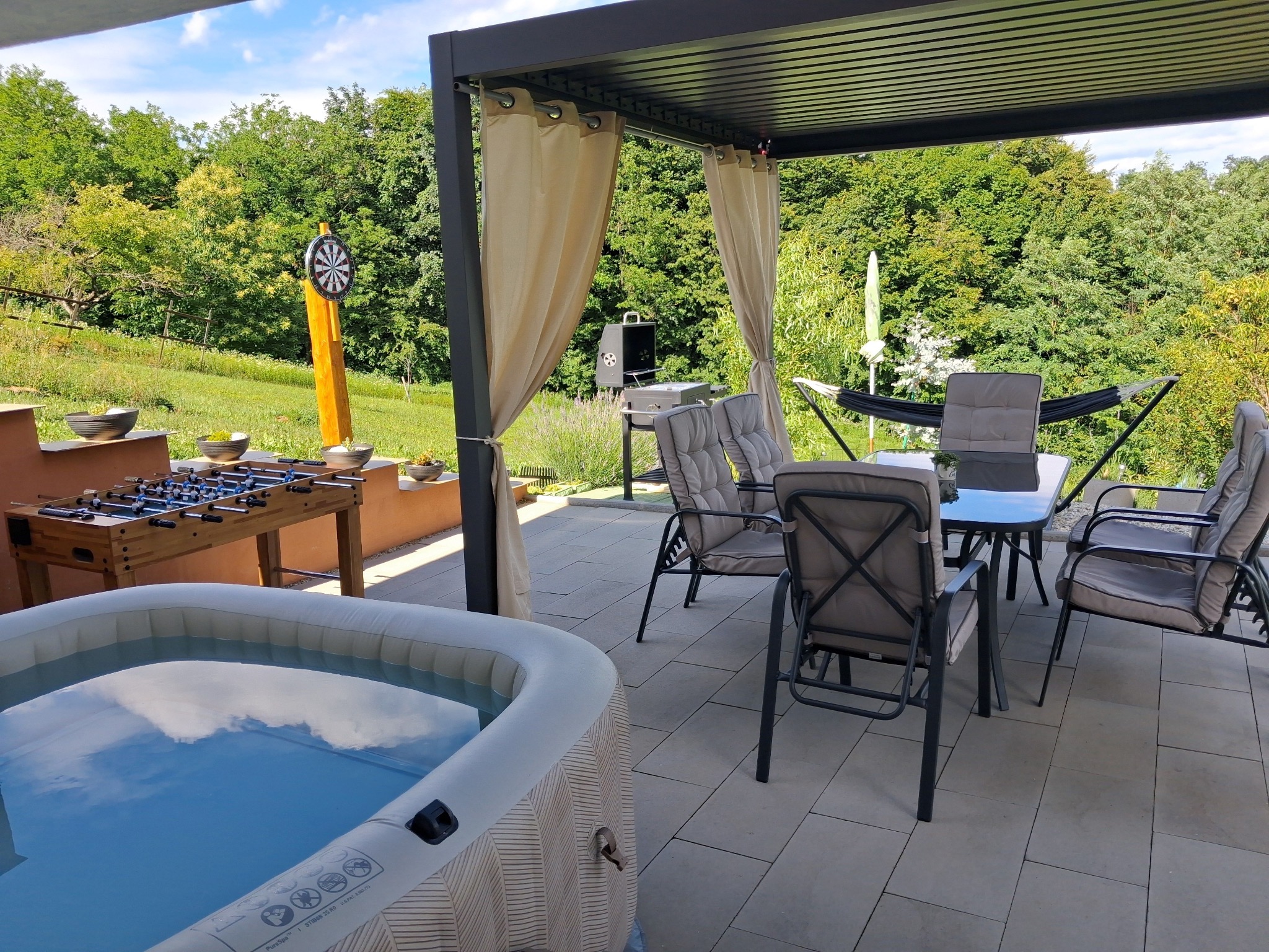 Terrasse mit Whirlpool, Sitzbereich und Gartenblick
